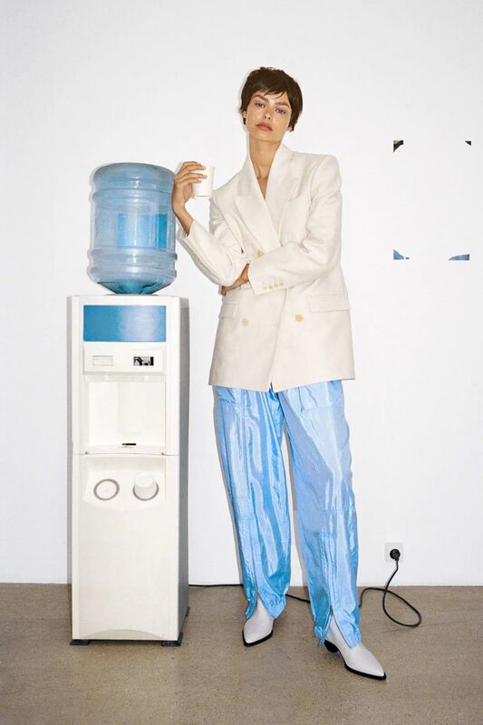 Inspiration: model in a cream blazer and blue satin trousers leaning on an office water cooler