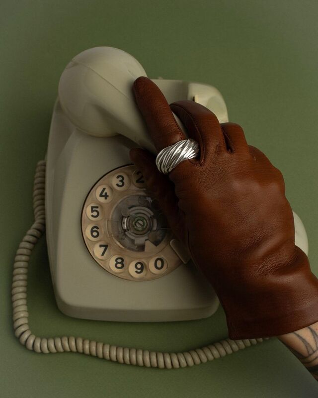 Inspiration: gloved hand holding a vintage rotary phone on an olive backdrop