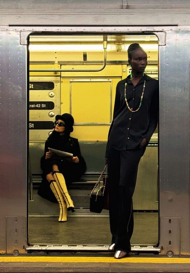 Two women in black and mustard boots in a yellow-lit subway car