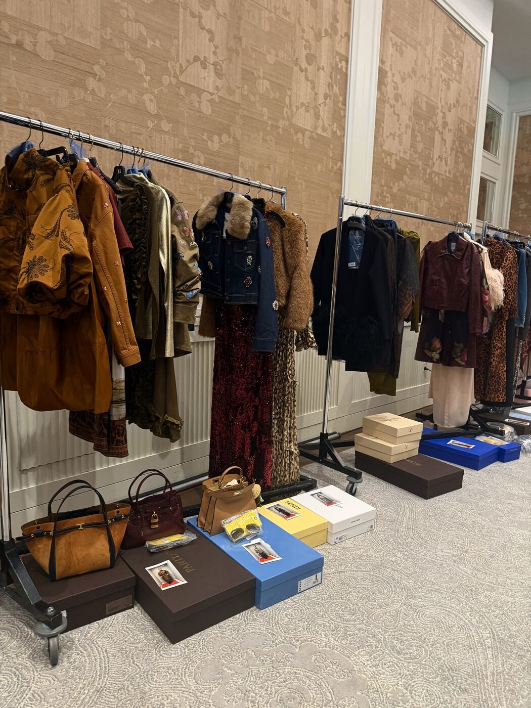 Racks of styled looks with shoes and handbags set beneath each one