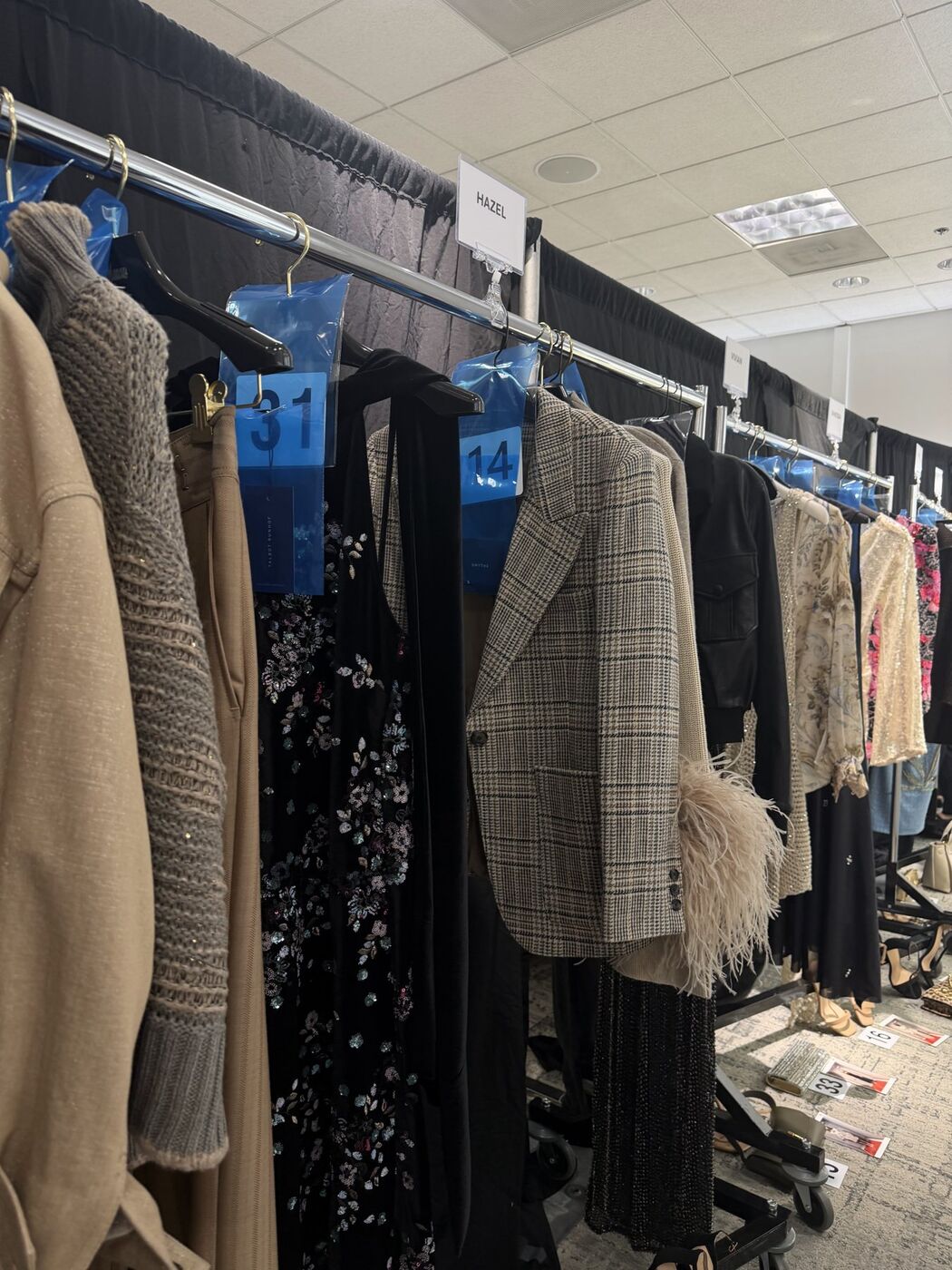 Numbered garment bags and coats on rolling racks backstage