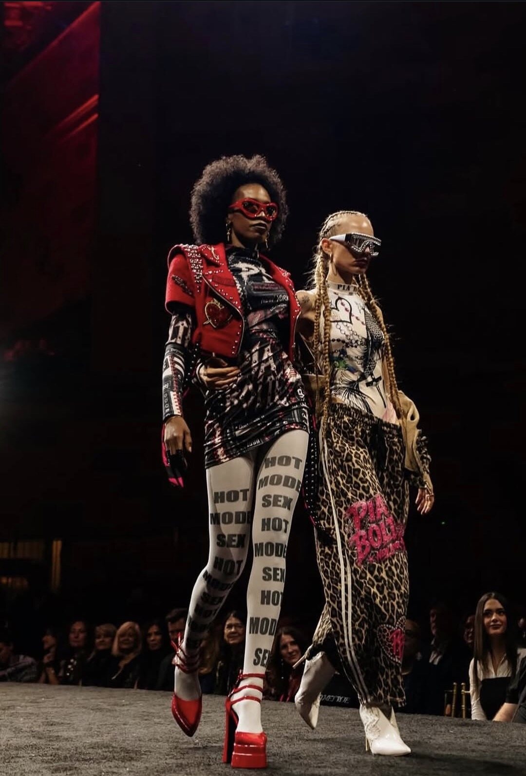 Two models in a studded red jacket and leopard-print track pants on the runway at The Bureau Fashion Week