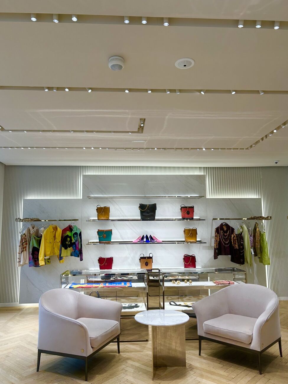 Boutique interior with colorful bags on lit shelving and lounge chairs