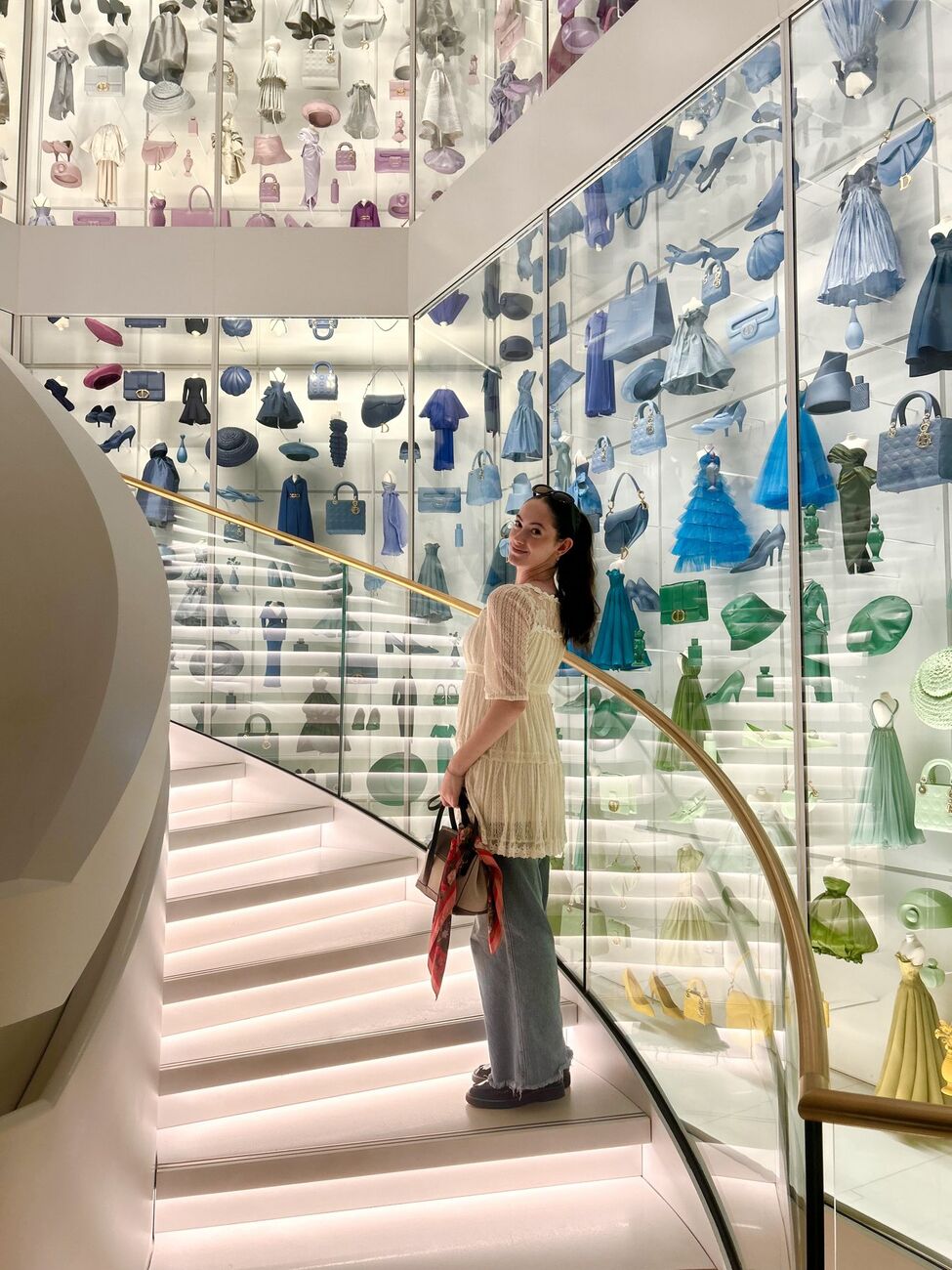 Angelina on the staircase at La Galerie Dior, surrounded by a wall of miniature Dior designs