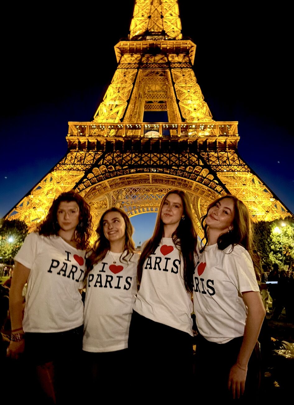 Angelina and three friends in I love Paris tees under the lit Eiffel Tower
