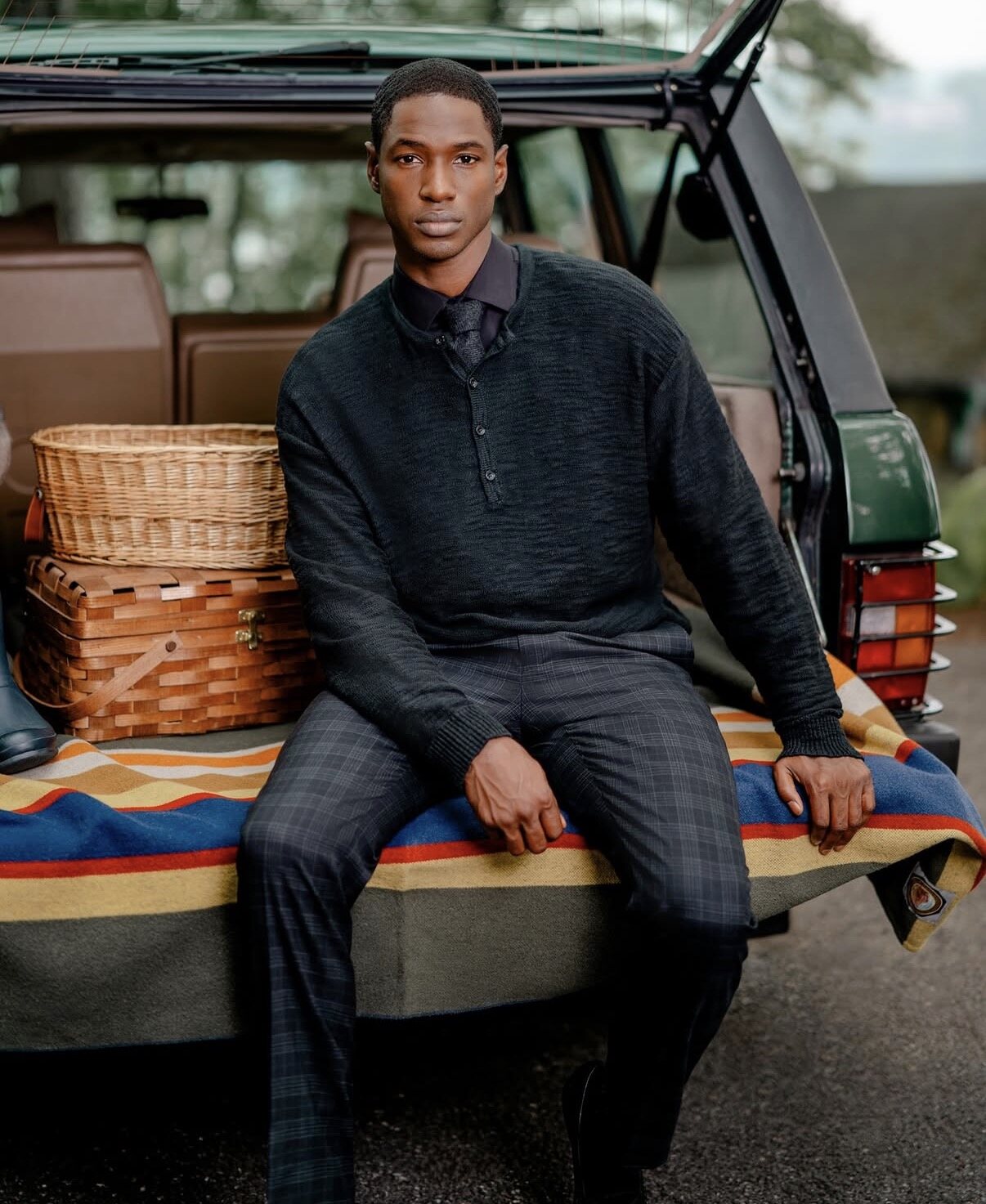 Hickey Freeman campaign image of a model on the tailgate of a vintage Land Rover