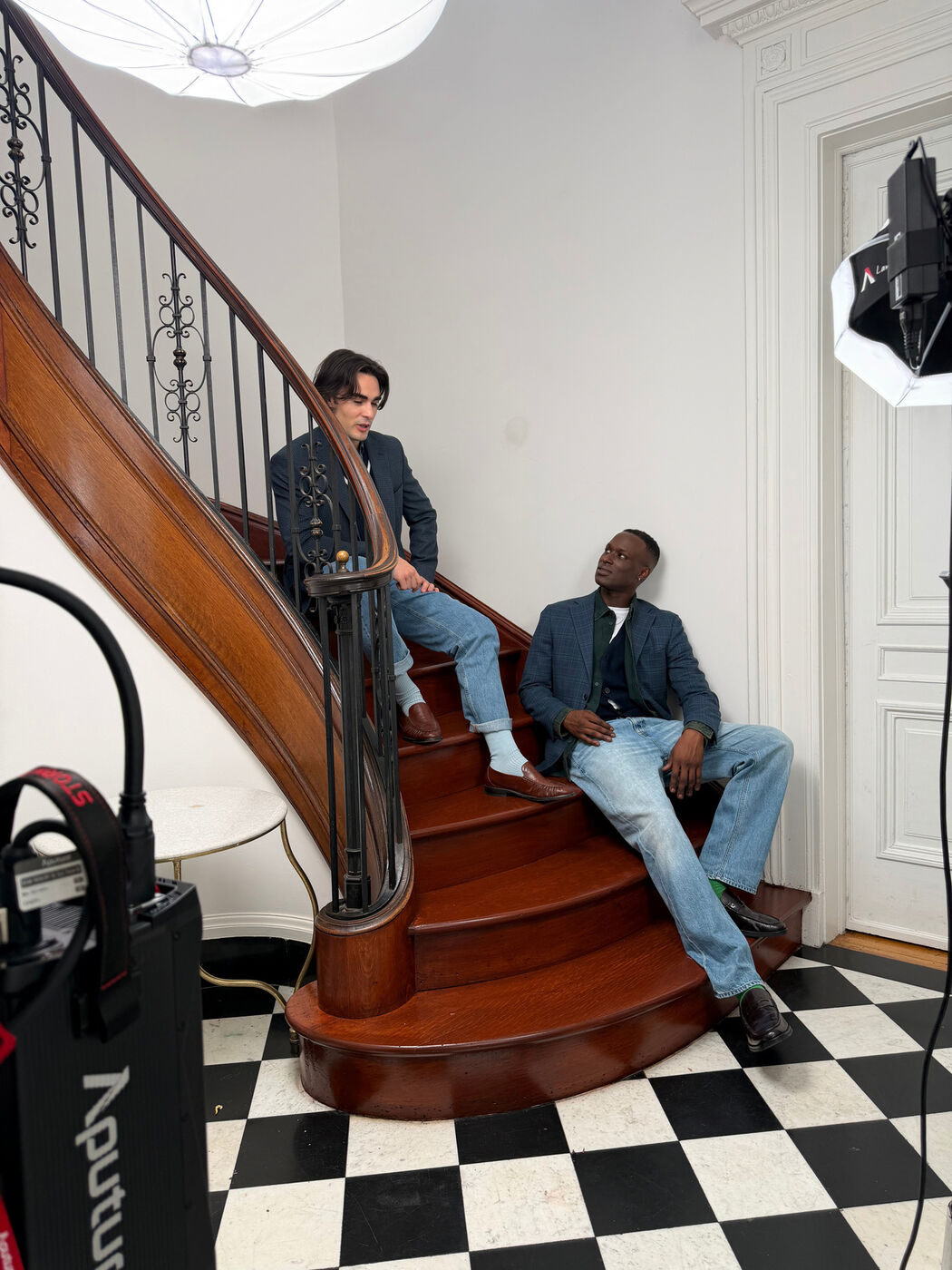 Two models in denim and tailoring on a spiral staircase