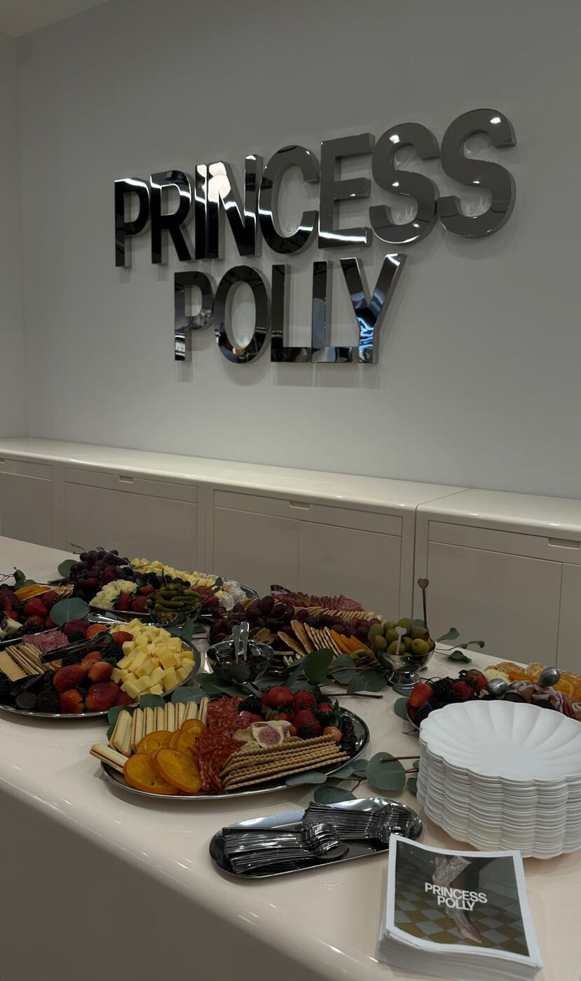 Grazing table under the mirrored Princess Polly sign with lookbooks and scalloped plates
