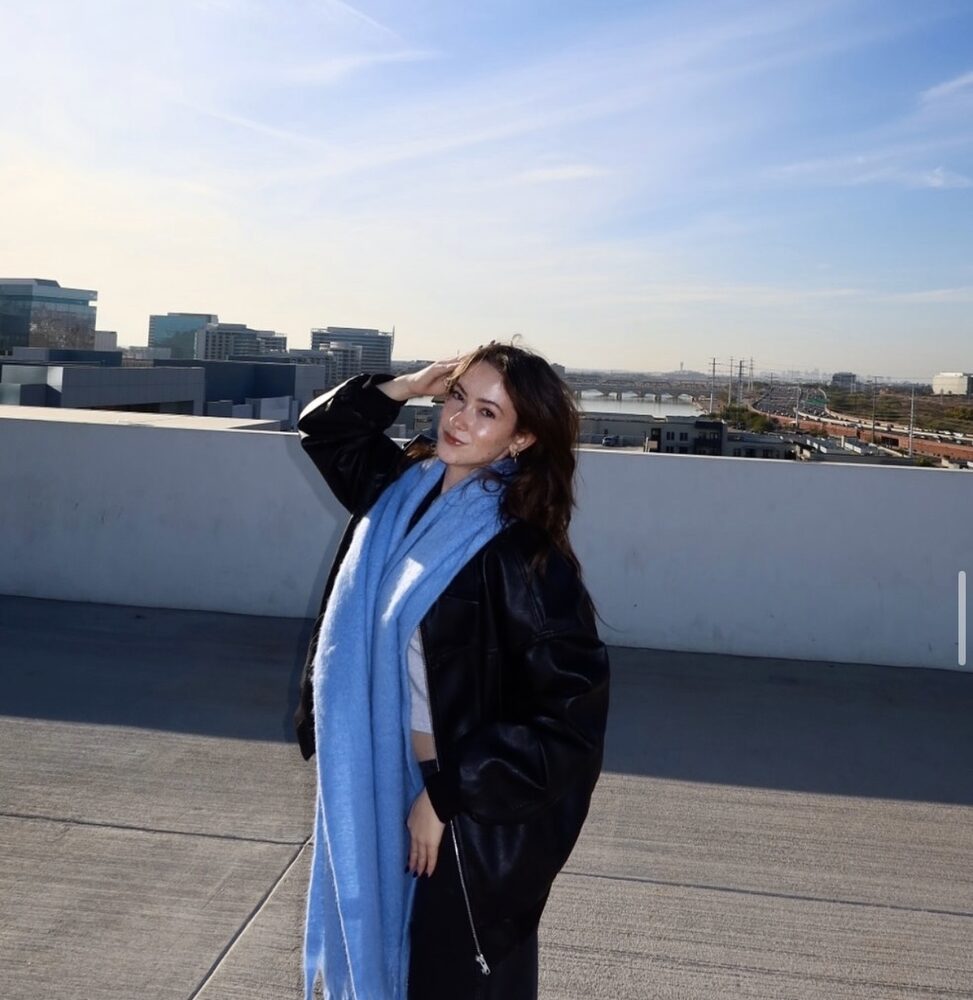 Oversized black leather jacket with a long blue scarf on a rooftop