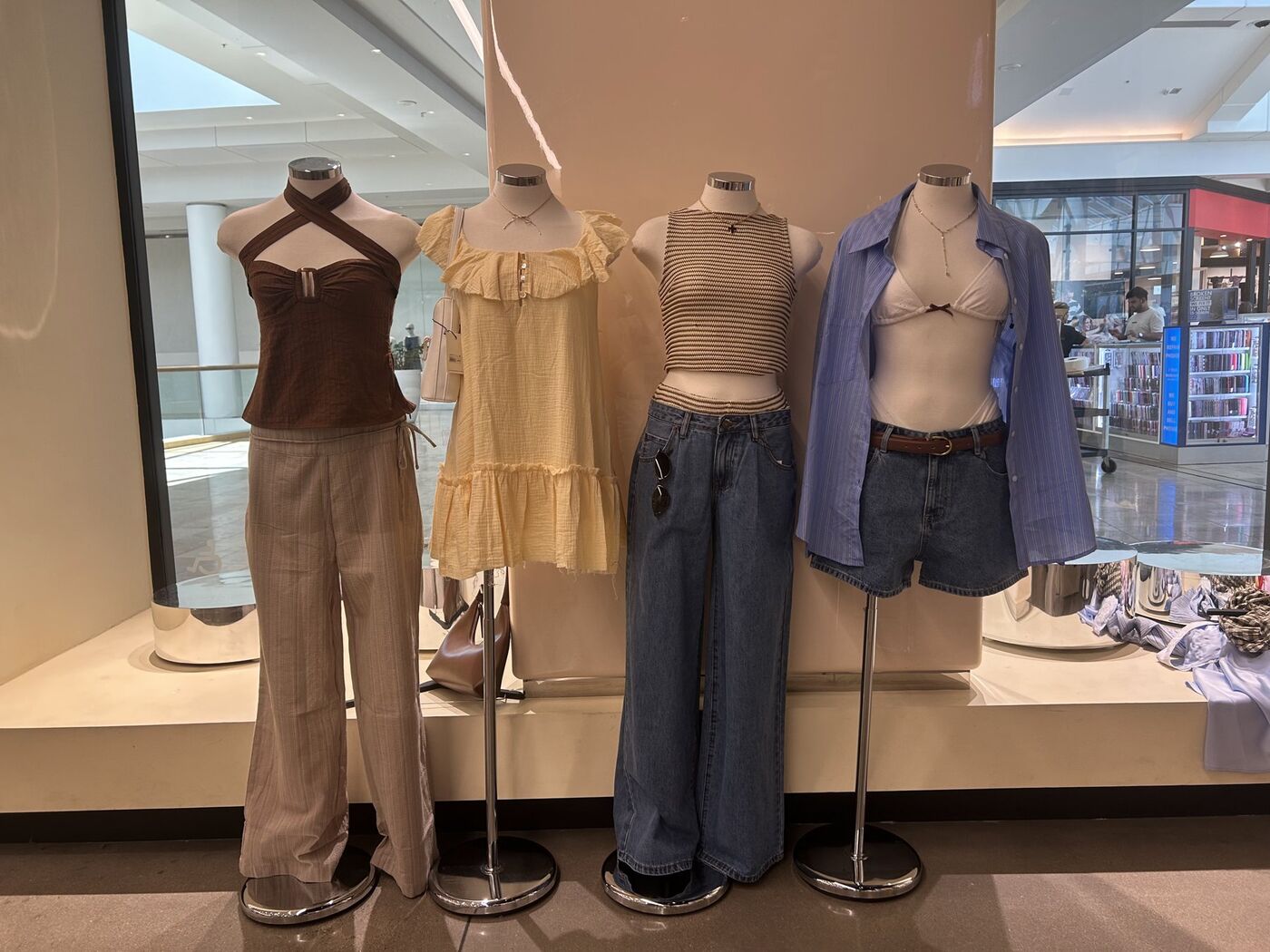 Four mannequins in brown, butter yellow and denim looks on a display platform