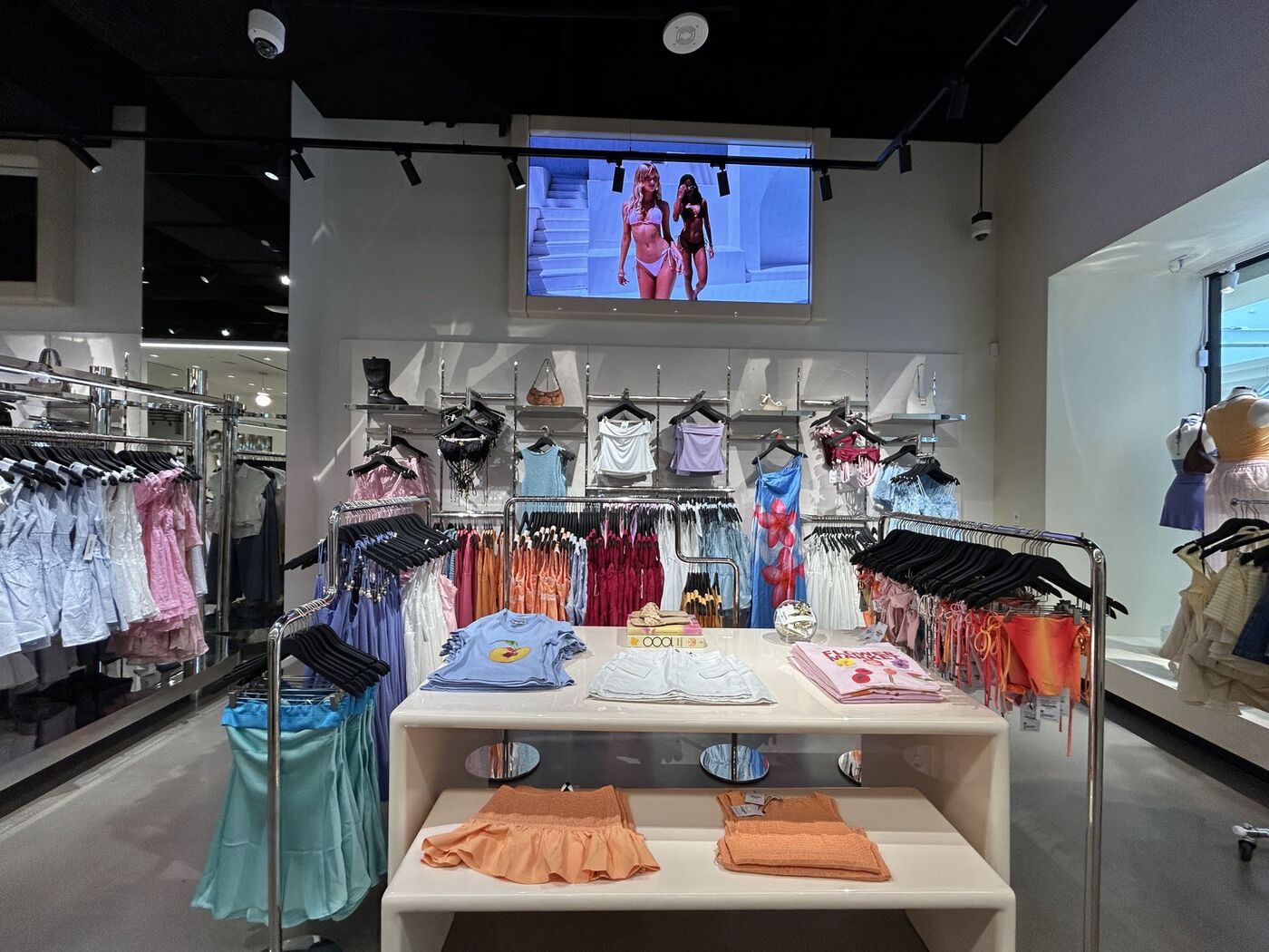 Merchandised wall of swimwear and tops with a folded table display